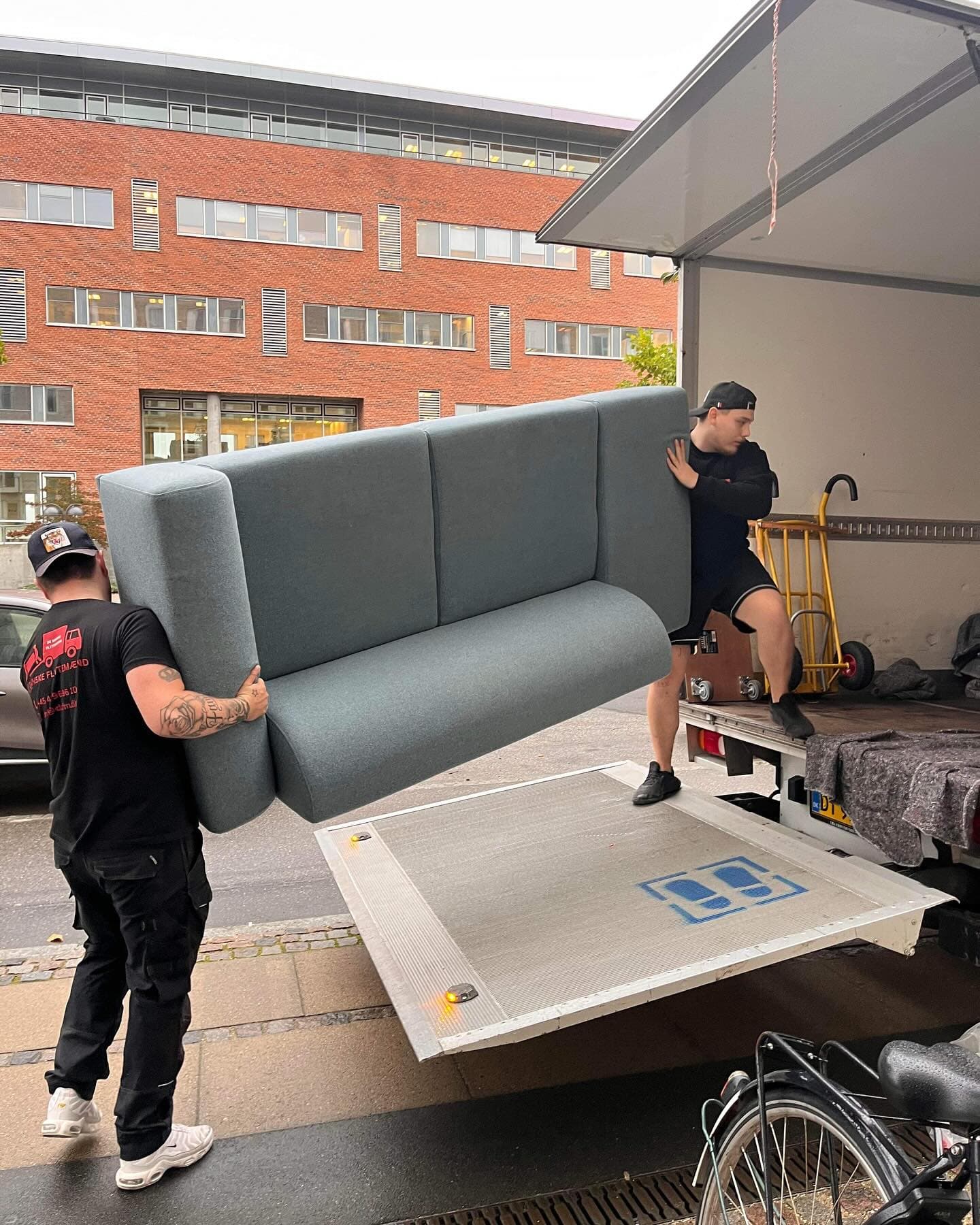 To flyttemænd løfter en sofa op på liften